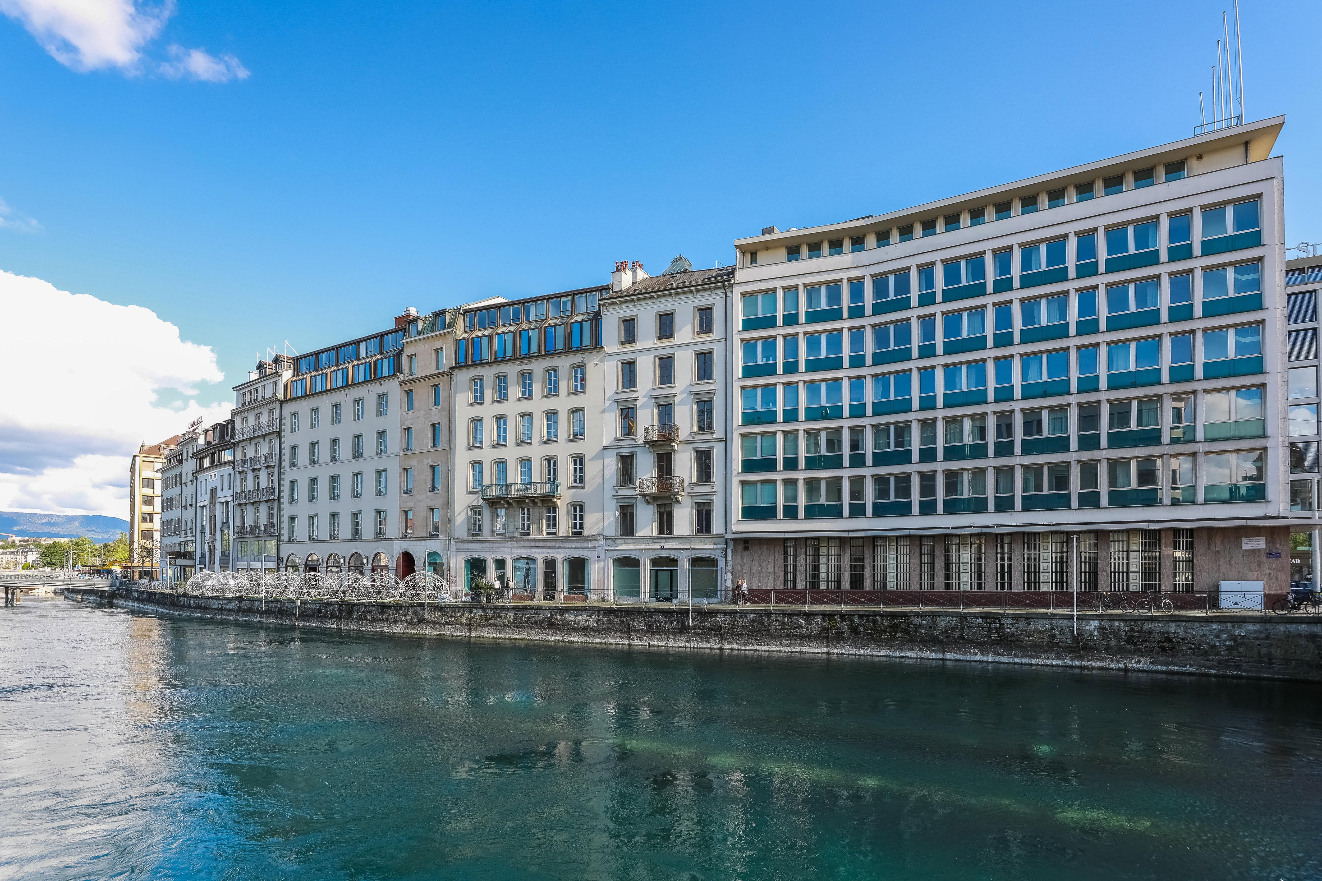 Ein Blick auf ein modernes Gebäude neben einem Wasserlauf unter blauem Himmel. Ein Blick auf ein modernes Gebäude neben einem Wasserlauf unter blauem Himmel.